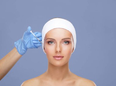 Genç bir kadının güzel yüzüne iğne yapan bir doktor. Estetik ameliyat, cilt gerdirme ve estetik tıp konsepti.