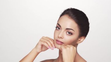 Beyaz arka planda genç ve güzel esmer bir kadının stüdyo portresi. Cilt bakımı ve sağlık kavramları.