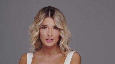 Gri arka planda genç ve güzel sarışın kadının stüdyo portresi. Cilt bakımı ve sağlık kavramları.