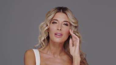 Gri arka planda genç ve güzel sarışın kadının stüdyo portresi. Cilt bakımı ve sağlık kavramları.