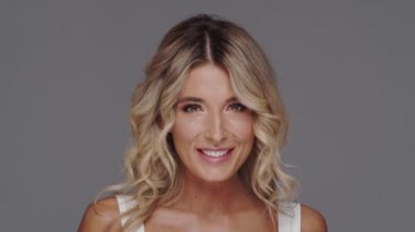 Gri arka planda genç ve güzel sarışın kadının stüdyo portresi. Cilt bakımı ve sağlık kavramları.