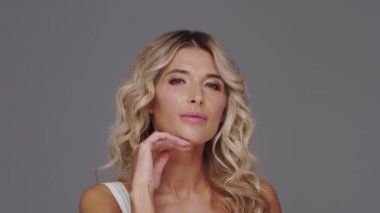 Gri arka planda genç ve güzel sarışın kadının stüdyo portresi. Cilt bakımı ve sağlık kavramları.