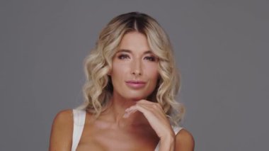 Gri arka planda genç ve güzel sarışın kadının stüdyo portresi. Cilt bakımı ve sağlık kavramları.