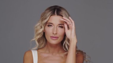 Gri arka planda genç ve güzel sarışın kadının stüdyo portresi. Cilt bakımı ve sağlık kavramları.