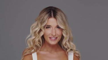 Gri arka planda genç ve güzel sarışın kadının stüdyo portresi. Cilt bakımı ve sağlık kavramları.