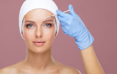 Genç bir kadının güzel yüzüne iğne yapan bir doktor. Estetik ameliyat, cilt gerdirme ve estetik tıp konsepti.