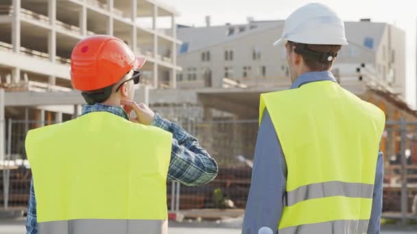 Professzionális Építők Állnak Építkezés Előtt Foreman Építőmérnök Keménykalapban Mellényben Irodaépület — Stock videók