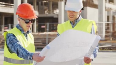 İnşaat alanının önünde duran profesyonel inşaatçılar. Ustabaşı ve inşaat mühendisi. Ofis binası ve vinç arka planı. İş, gayrimenkul ve yatırım kavramları.