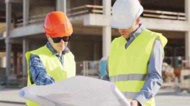 İnşaat alanının önünde duran profesyonel inşaatçılar. Ustabaşı ve inşaat mühendisi. Ofis binası ve vinç arka planı. İş, gayrimenkul ve yatırım kavramları.