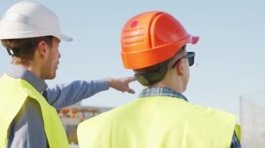 İnşaat alanının önünde duran profesyonel inşaatçılar. Ustabaşı ve inşaat mühendisi. Ofis binası ve vinç arka planı. İş, gayrimenkul ve yatırım kavramları.