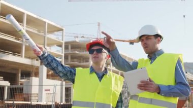 İnşaat alanının önünde duran profesyonel inşaatçılar. Ustabaşı ve inşaat mühendisi. Ofis binası ve vinç arka planı. İş, gayrimenkul ve yatırım kavramları.