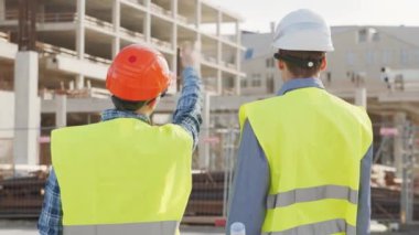 İnşaat alanının önünde duran profesyonel inşaatçılar. Ustabaşı ve inşaat mühendisi. Ofis binası ve vinç arka planı. İş, gayrimenkul ve yatırım kavramları.