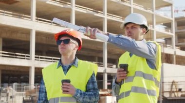 İnşaat alanının önünde duran profesyonel inşaatçılar. Ustabaşı ve inşaat mühendisi. Ofis binası ve vinç arka planı. İş, gayrimenkul ve yatırım kavramları.