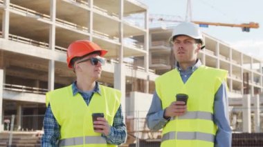 İnşaat alanının önünde duran profesyonel inşaatçılar. Ustabaşı ve inşaat mühendisi. Ofis binası ve vinç arka planı. İş, gayrimenkul ve yatırım kavramları.