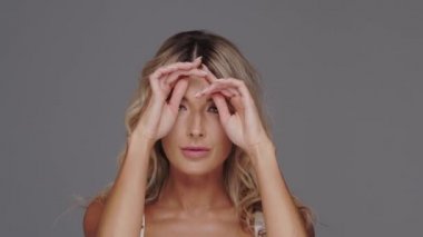 Gri arka planda genç, güzel ve anlamlı sarışın bir kadının stüdyo portresi..