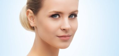 Mavi arka planda güzel bir kızın yüzü. Estetik cerrahi, cilt gerdirme, kaplıca, kozmetik ve tıp konsepti.