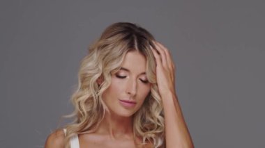 Gri arka planda genç, güzel, üzgün kadın.