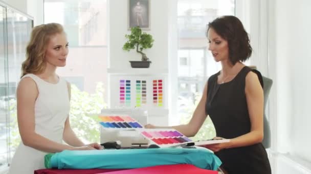 Een klant en een naaister kiezen een stof in een kleermakerij. — Stockvideo
