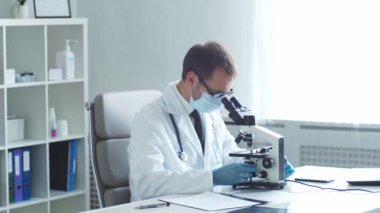 Hastane ofisinde mikroskop kullanarak çalışan profesyonel tıp doktoru. Tıp ve sağlık hizmetleri kavramları.