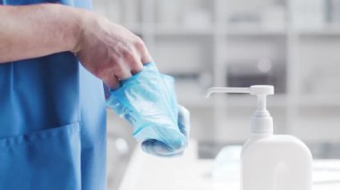 Doktorun eldivenlerini çıkardığı yakın çekim. Hastanedeki ofis arka planda..