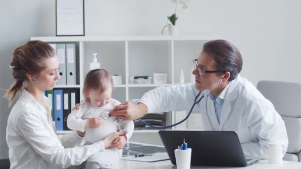 Pediatra bada chore dziecko. Lekarz, matka i córka w gabinecie lekarskim w klinikach. — Wideo stockowe