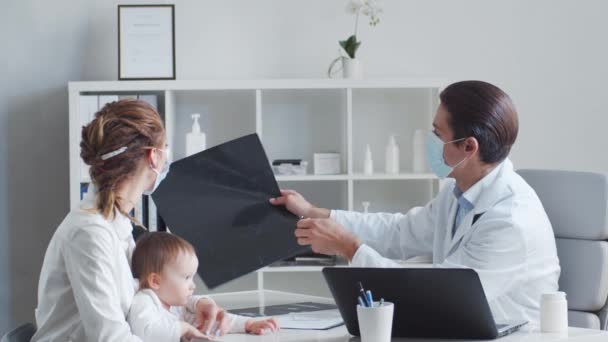 O pediatra está a examinar o bebé doente. Médico, mãe e filha em consultório médico em clínicas. — Vídeo de Stock