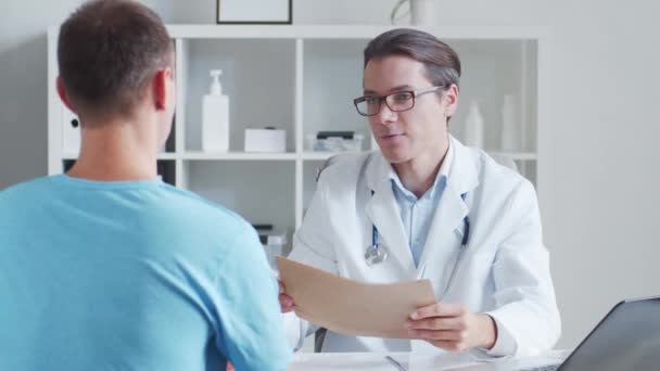 Pediatr vyšetřuje mladého muže. Lékař a pacient na klinice. — Stock video