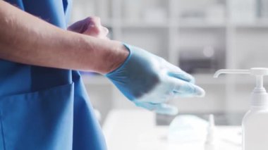 Doktorun eldiven giyip, tıbbi sabunla dezenfektan kullandığına yakın çekim. Ofis hastanede, arka planda. Virüs koruma kavramı.