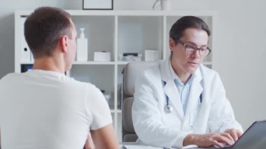 Erkek çocuk doktoru genç bir adamı muayene ediyor. Klinikteki doktor ve hasta. Sağlık hizmetleri kavramı.