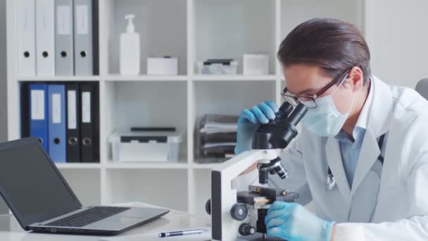 Professionele arts die in het laboratorium werkt met behulp van microscoop. — Stockvideo