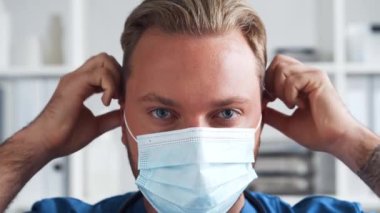 Hastane ofisinde çalışan profesyonel tıp doktoru koruyucu maskeli genç ve kendinden emin bir doktorun portresi..