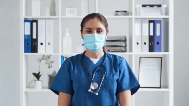 병원에서 근무하는 전문 의사, 보호용 마스크를 쓰고 있는 젊고 매력적 인 여성 의사의 모습. — 비디오