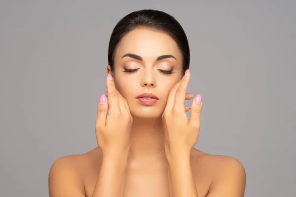 Rosto de uma linda menina morena. Retrato de mulher jovem e atraente sobre fundo cinza. — Fotografia de Stock