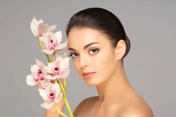 Rosto de uma linda menina morena. Retrato de mulher jovem e atraente sobre fundo cinza. — Fotografia de Stock