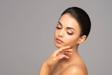 Güzel esmer bir kızın yüzü. Gri arka planda genç ve çekici bir kadının portresi.