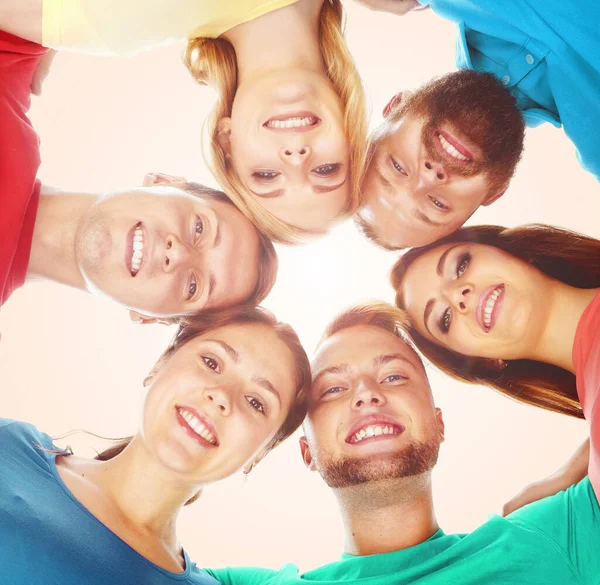 Glückliche, lächelnde Freunde, die zusammen stehen und vor orangefarbenem Hintergrund in die Kamera schauen. — Stockfoto