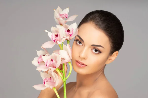 Rosto de uma linda menina morena. Retrato de mulher jovem e atraente sobre fundo cinza. — Fotografia de Stock