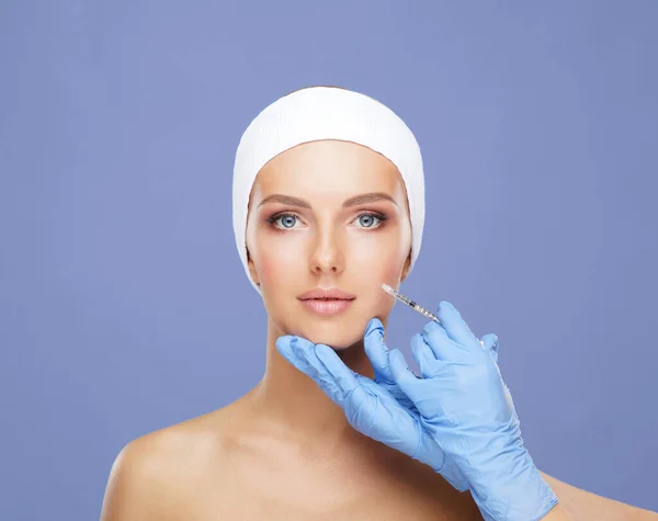 Arzt spritzt einer jungen Frau eine Spritze ins schöne Gesicht. Plastische Chirurgie. — Stockfoto
