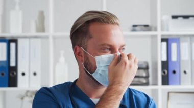 Hastane ofisinde çalışan profesyonel tıp doktoru koruyucu maskeli genç ve kendinden emin bir doktorun portresi..
