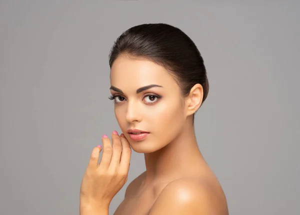 Face of a beautiful brunette girl. Portrait of young and attractive woman over grey background.