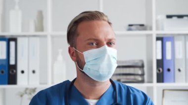 Hastane ofisinde profesyonel tıp doktoru koruyucu maskeli genç ve kendinden emin bir doktorun portresi..