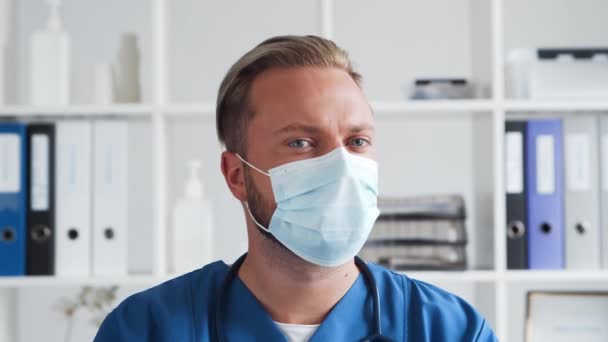 Professionele arts in het ziekenhuis kantoor, Portret van jonge en zelfverzekerde arts in beschermend masker. — Stockvideo
