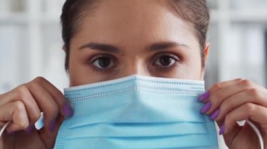 Hastane ofisinde profesyonel tıp doktoru koruyucu maskeli genç ve çekici bir kadın doktorun portresi..