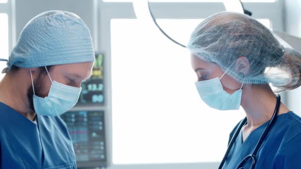 Orvosok, akik a sürgősségi orvosláson dolgoznak. A sebész és a sebészeti beavatkozást végző védőmaszkos nővér portréja. — Stock videók