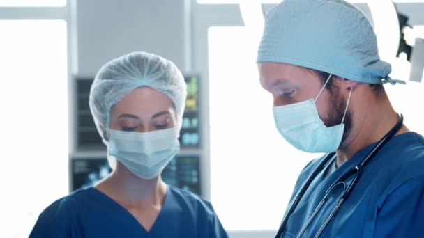 Професійні лікарі-медики, що працюють в екстреній медицині. Портрет хірурга і медсестри в захисних масках, що виконують хірургічну операцію . — стокове відео
