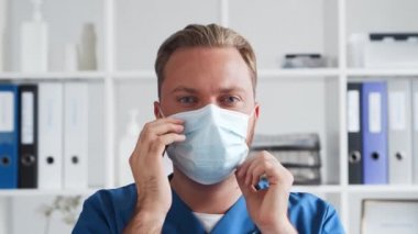 Hastane ofisinde profesyonel tıp doktoru koruyucu maskeli genç ve kendinden emin bir doktorun portresi..