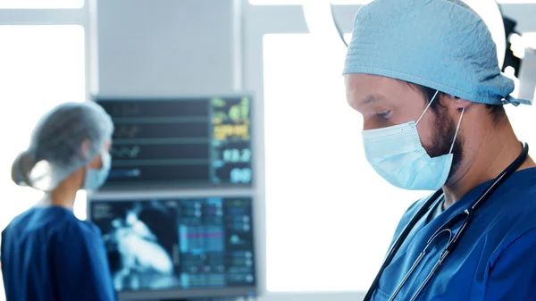 Médecins professionnels travaillant en médecine d'urgence. Portrait du chirurgien et de l'infirmière dans des masques protecteurs effectuant une opération chirurgicale. — Photo