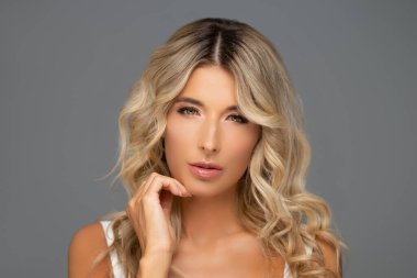 Gri arka planda genç ve güzel bir kadının stüdyo portresi.