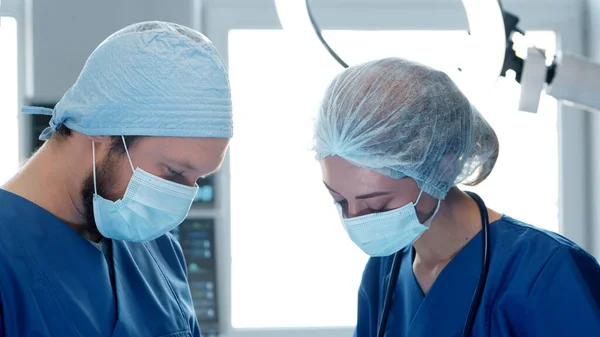 Médicos profesionales que trabajan en medicina de emergencia. Retrato del cirujano y la enfermera en máscaras protectoras realizando operación quirúrgica. — Foto de Stock