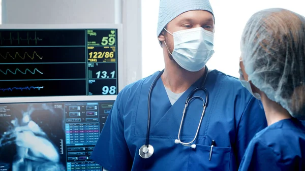 Médecins professionnels travaillant en médecine d'urgence. Portrait du chirurgien et de l'infirmière dans des masques protecteurs effectuant une opération chirurgicale. — Photo